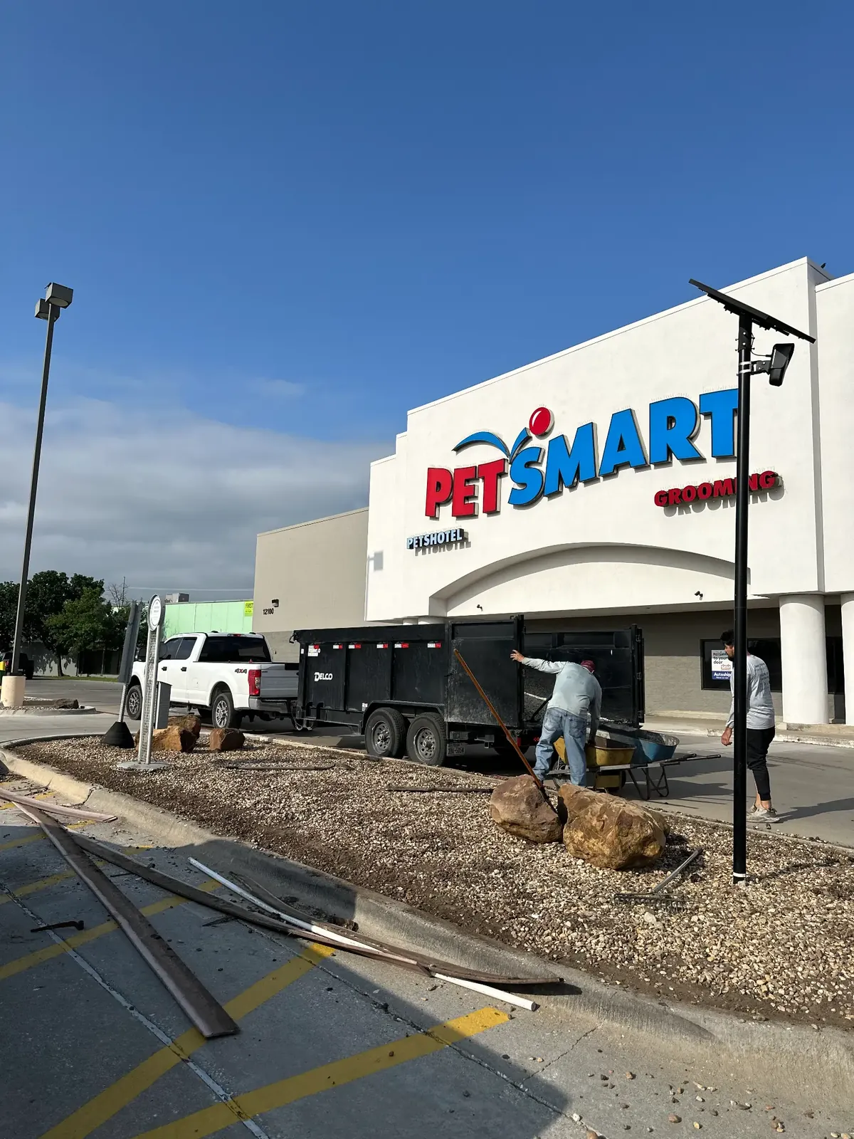 Godoy's Wolves crew member with a wheelbarrow working a PetSmart parking-lot island