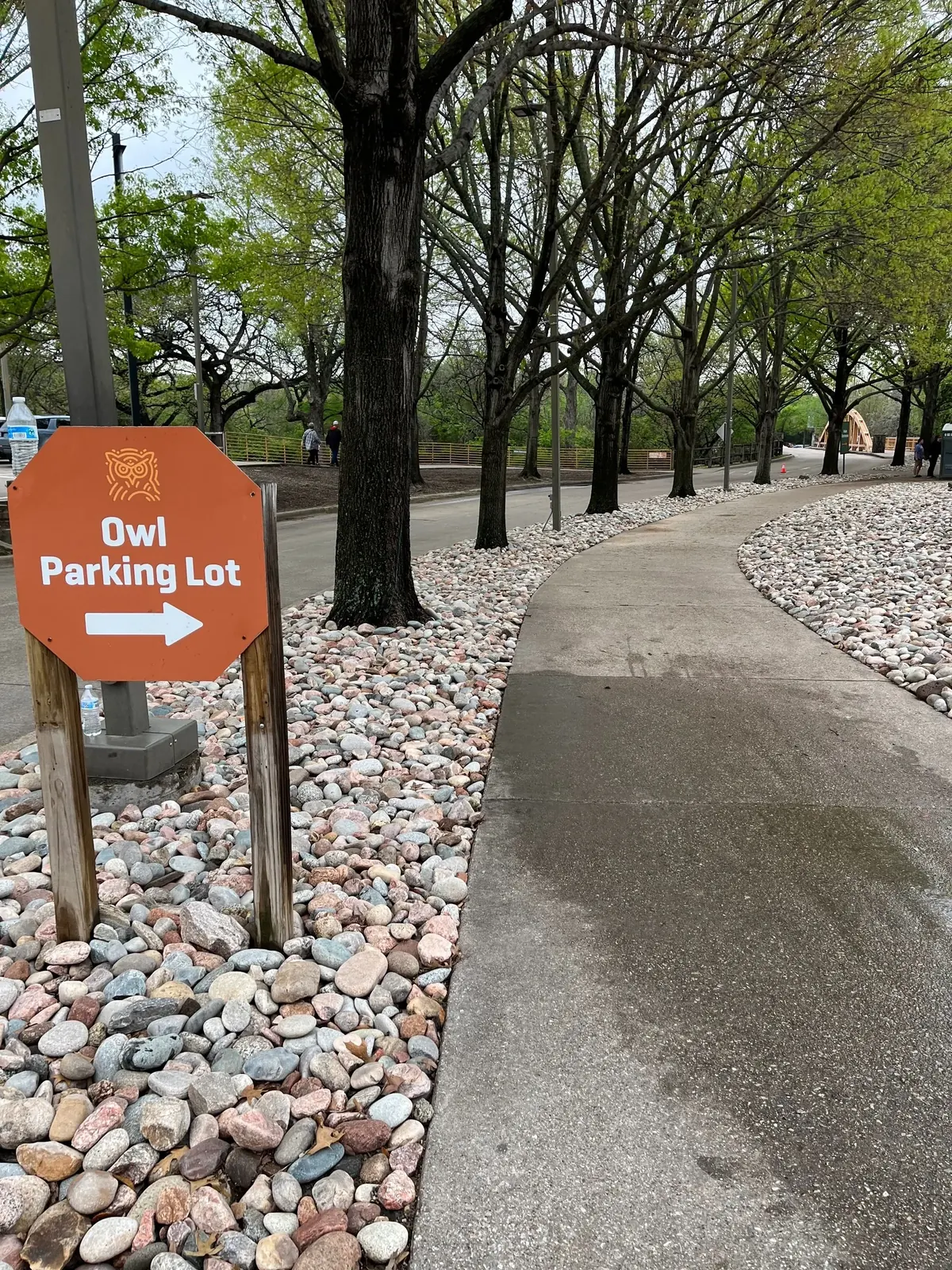 River rock beds installed either side of a wayfinding sign on a commercial parking campus, DFW