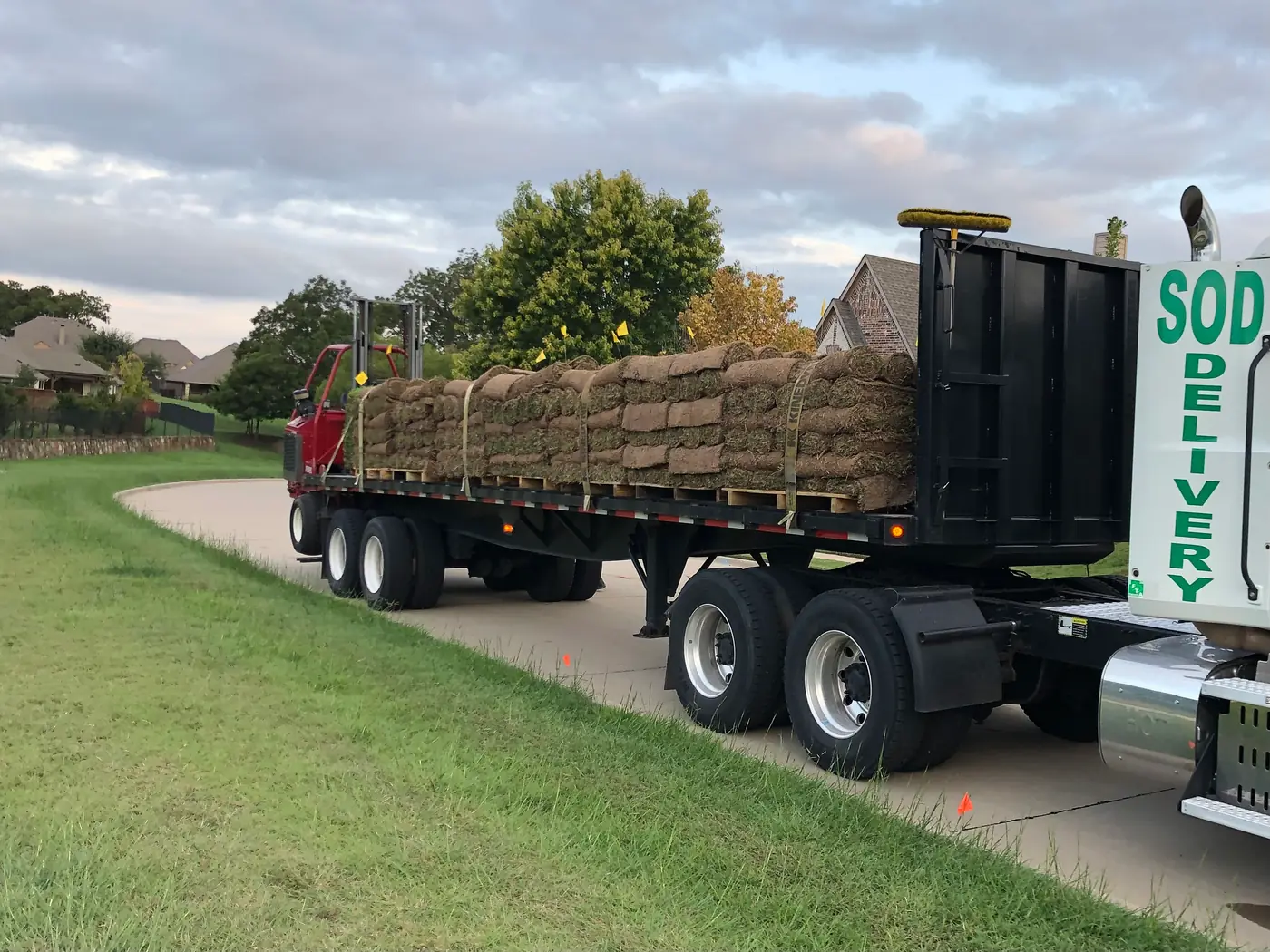 Flatbed semi trailer loaded with pallets of sod arriving at a commercial job site