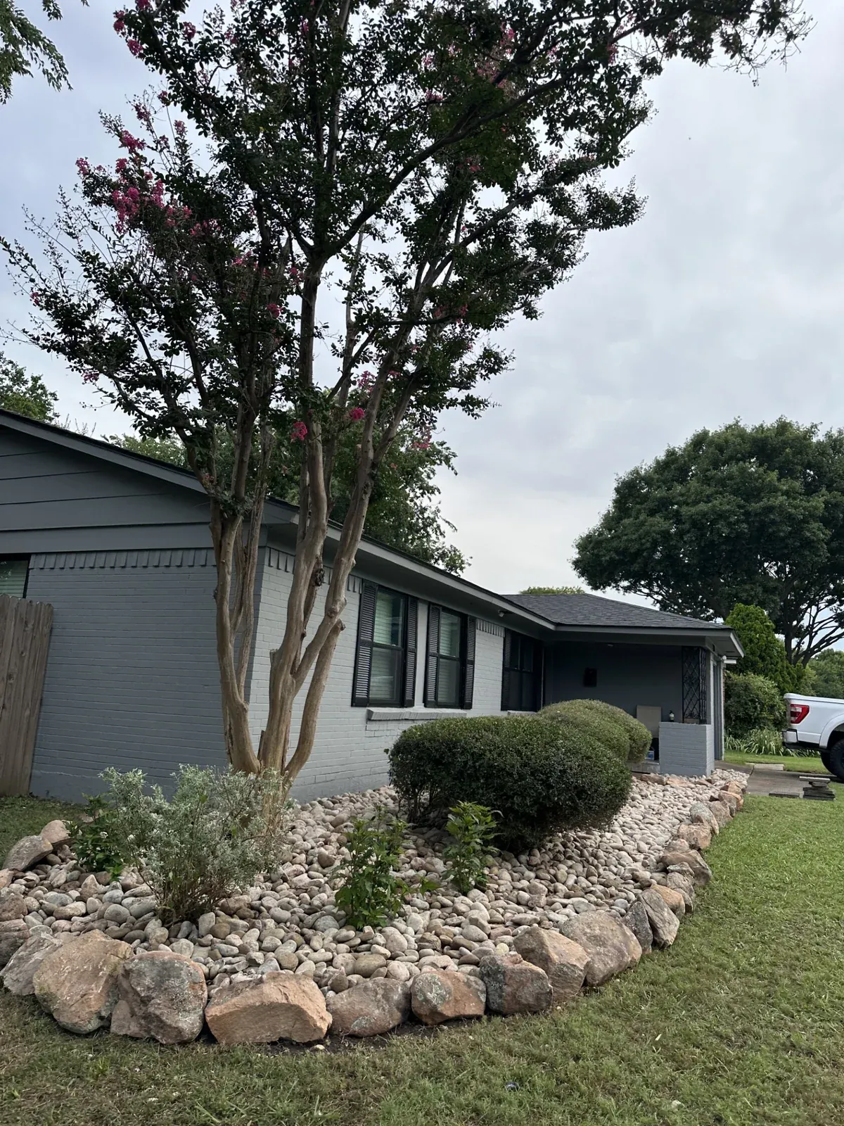 River rock front-yard bed with crape myrtle and shrubs at a Dallas home, Godoy's Wolves