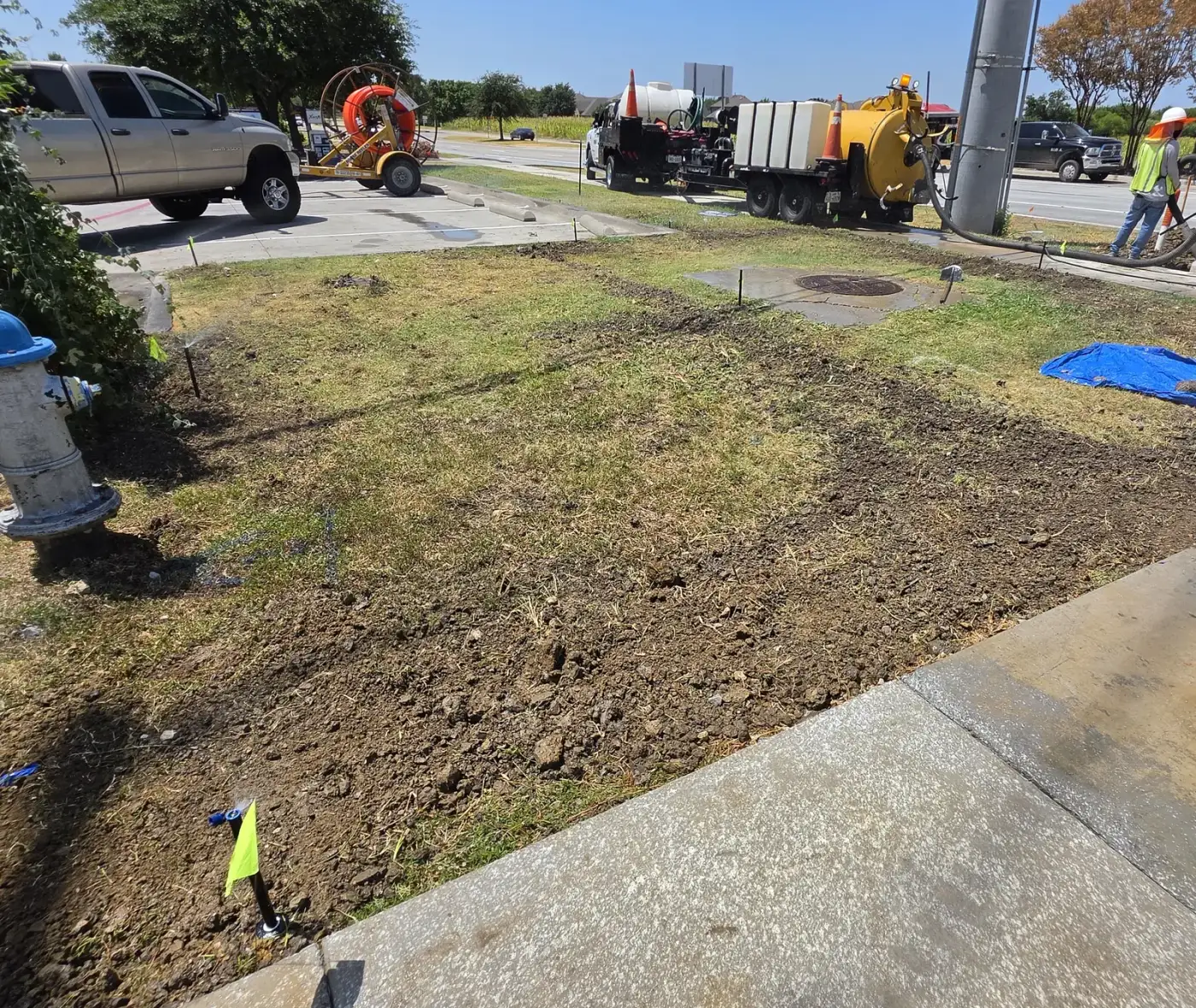 Vacuum excavation truck and hi-vis crew working an irrigation main along a commercial roadway